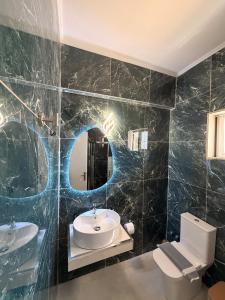 a bathroom with a sink and a toilet and a mirror at Rafael & Sofia Luxury Suites in Ammoudia +19 photos