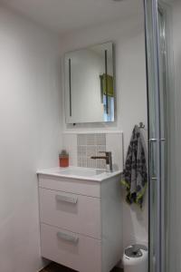 a white bathroom with a sink and a mirror at Collis Annexe in Didcot