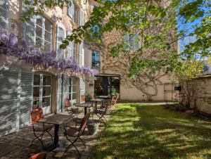 a patio with tables and chairs in front of a building at Hôtel Le Quatorze in Figeac