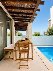 a wooden table and chairs on a patio with a pool at athanasian side sea view home in Polychrono