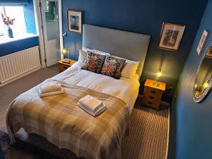 a blue bedroom with a bed with two towels on it at The Red Lion Hotel in Oakford