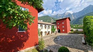 a red and white building with mountains in the background at Maso Montel in Barco