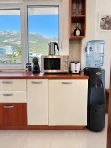 a kitchen with a counter with a microwave and a refrigerator at Penthouse Bečići Apartament in Bečići
