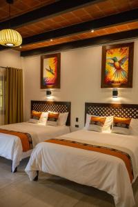 a bedroom with two beds and two paintings on the wall at Rincon del Buey Resort in Copán Ruinas