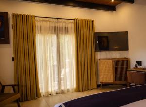 a bedroom with a large window with yellow curtains at Rincon del Buey Resort in Copán Ruinas