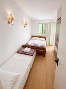 two beds in a room with white walls and wooden floors at Vila Petra in Perazića Do
