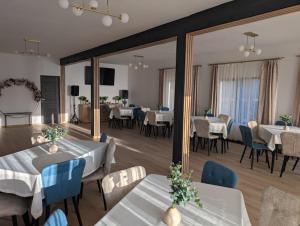 a dining room with white tables and blue chairs at Cabana Ozon in Sărmaş