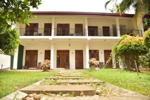 a white building with wooden doors and a walkway at Buddika Safari & Resort in Udawalawe