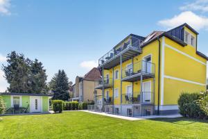 a yellow apartment building with a green yard at AJO Apartments - Vetmed - Self-Check-in in Vienna
