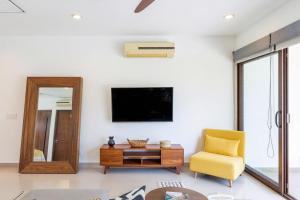 a living room with a tv and a yellow chair at Bright 1 BD with private Terrace near TULUM in Akumal