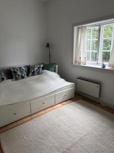 a white bedroom with a bed and two windows at The South Wing at Højbygård in Rødby