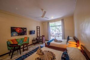 a room with two beds and a couch and a window at Double A Nungwi Beach Hotel - Beach Front in Nungwi
