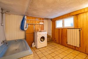 a bathroom with a tub and a washing machine at On The Rocks - Alpes Mancelles - Jardin in Sillé-le-Guillaume