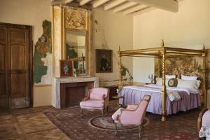 a bedroom with a bed and two chairs and a fireplace at Chateau de Gudanes in Château-Verdun