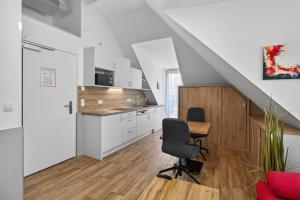 a kitchen with white cabinets and a table and a chair at AJO Apartments - Vetmed - Self-Check-in in Vienna +14 photos