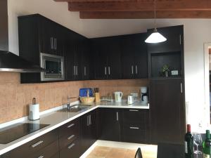 a kitchen with black cabinets and white counter tops at Casa el Durazno in Lodero