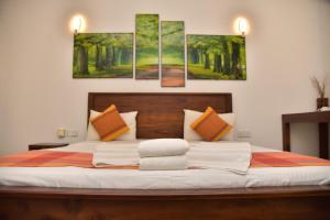 a bedroom with a bed with four paintings on the wall at Buddika Safari & Resort in Udawalawe