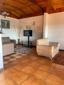 a living room with two couches and a flat screen tv at Casa Eliza in Alajuela