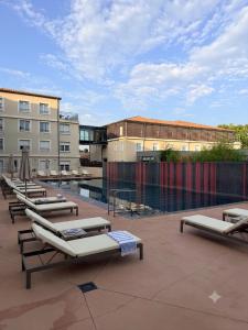 a row of chaise lounges on a patio with a pool at Côté green in Juvignac