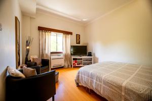 a bedroom with a bed and two chairs and a television at Travessa in Lisbon