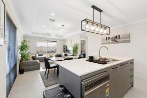 a kitchen with a sink and a living room at Drift at Shorehaven Coast in Alkimos