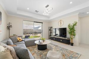 a living room with a couch and a tv at Drift at Shorehaven Coast in Alkimos