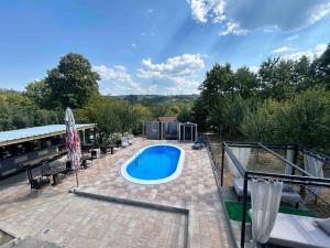 a swimming pool on a brick patio with chairs at VILLA M Rustic & Spa in Slatina Varoš