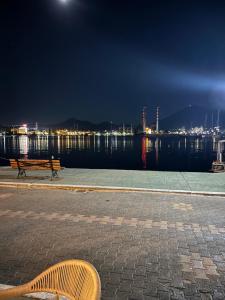 a bench sitting next to the water at night at The Old Winery in Aliveri +3 photos