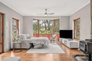 a white bedroom with a bed and a tv at The Retreat, Barossa Valley in Lights Pass