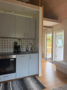 a kitchen with white cabinets and a living room at Charming cottage on Kvegero in Gnesta