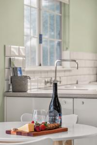 a bottle of wine sitting on a table with cheese and fruit at Grace Cottage, Barossa Valley in Lights Pass