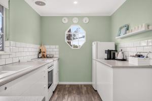 a white kitchen with a sink and a refrigerator at Grace Cottage, Barossa Valley in Lights Pass +10 photos