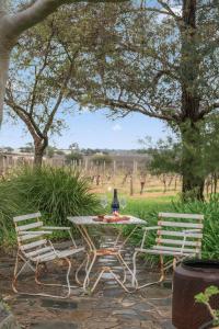 two chairs and a table with a wine bottle on it at Grace Cottage, Barossa Valley in Lights Pass