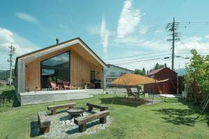 a house with benches and an umbrella in the yard at JOKIJOKI Hakuba in Hakuba