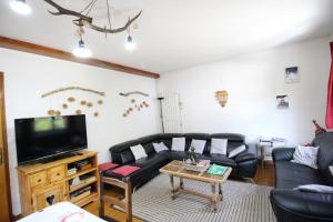 a living room with black leather furniture and a flat screen tv at Le Gite 5 mn de Luchon - Jardin garage et parking in Benque-Dessous-et-Dessus