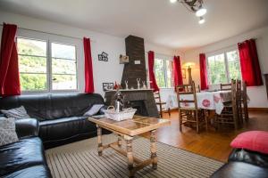 a living room with a black leather couch and a table at Le Gite 5 mn de Luchon - Jardin garage et parking in Benque-Dessous-et-Dessus