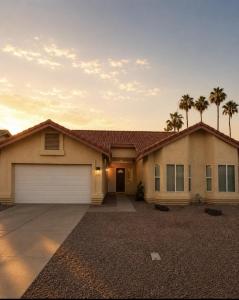a house with a garage with palm trees in the background at Desert Disconnect Pool and Putting Green in Gilbert