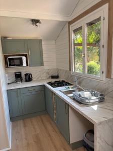 a kitchen with green cabinets and a stove top oven at Camping le Cabri in Duras