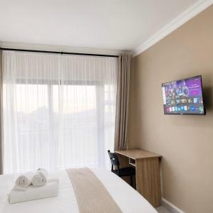 a hotel room with a bed and a television on the wall at Jets Stay Property in Cape Town