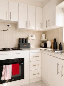 a kitchen with white cabinets and a red towel on the oven at Jets Stay Property in Cape Town