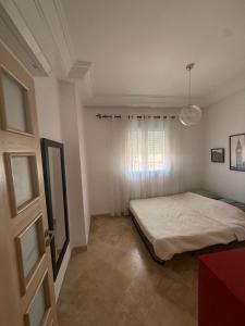 a bedroom with a bed and a window at Les pieds dans l eau, résidence Nadine in Hammam Sousse