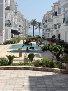 a swimming pool in front of some apartment buildings at Les pieds dans l eau, résidence Nadine in Hammam Sousse