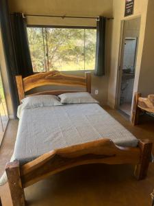 a wooden bed in a bedroom with a large window at Chale3 Rabodegalo in Santana do Riacho
