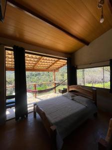 a bedroom with a bed and a large window at Chale3 Rabodegalo in Santana do Riacho