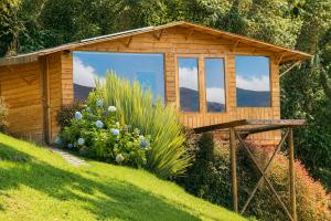 a small wooden shed with a window in a garden at Neusa Hills Eco Hotel Boutique in Tausa Viejo