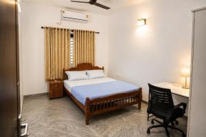 a bedroom with a bed and a desk and a chair at Hridyas in Ernakulam