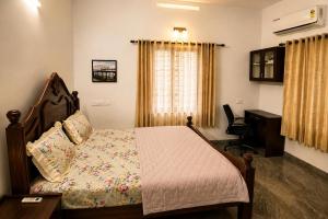a bedroom with a bed and a desk and a window at Hridyas in Ernakulam