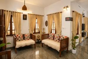 a living room with two chairs and two windows at Hridyas in Ernakulam +13 photos