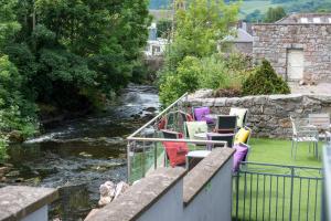 a group of chairs sitting on a balcony next to a river at The Birchtree Hotel in Dalbeattie