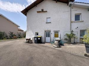 a white house with two benches next to a street at La Grande Chaumiere in Saint-Vulbas
